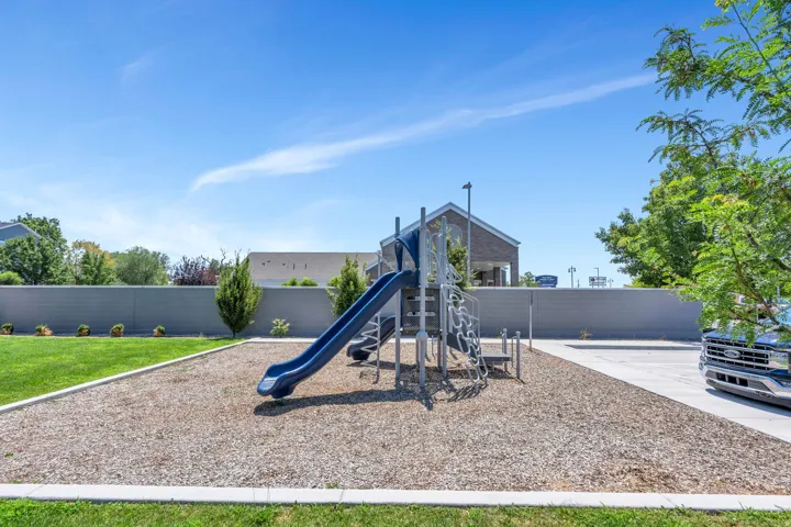 Outdoor playground structure featuring a blue slide and climbing elements on a wood chip surface
