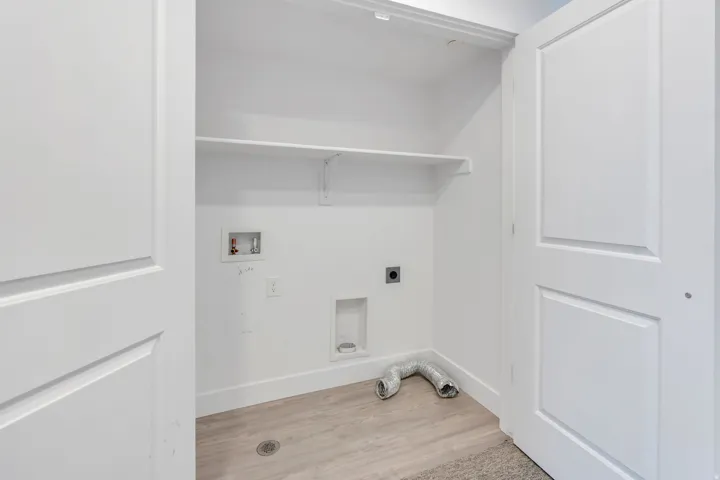Dedicated laundry closet featuring a white shelf, light wood-finish flooring, and panel doors
