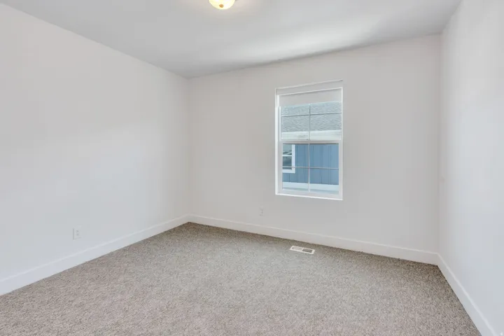 Carpeted room featuring a single window with blinds, white walls, white baseboards, and a ceiling light fixture