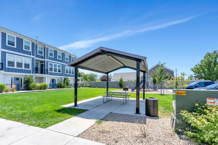 Community green space featuring a picnic shelter with a concrete pad and a metal picnic table