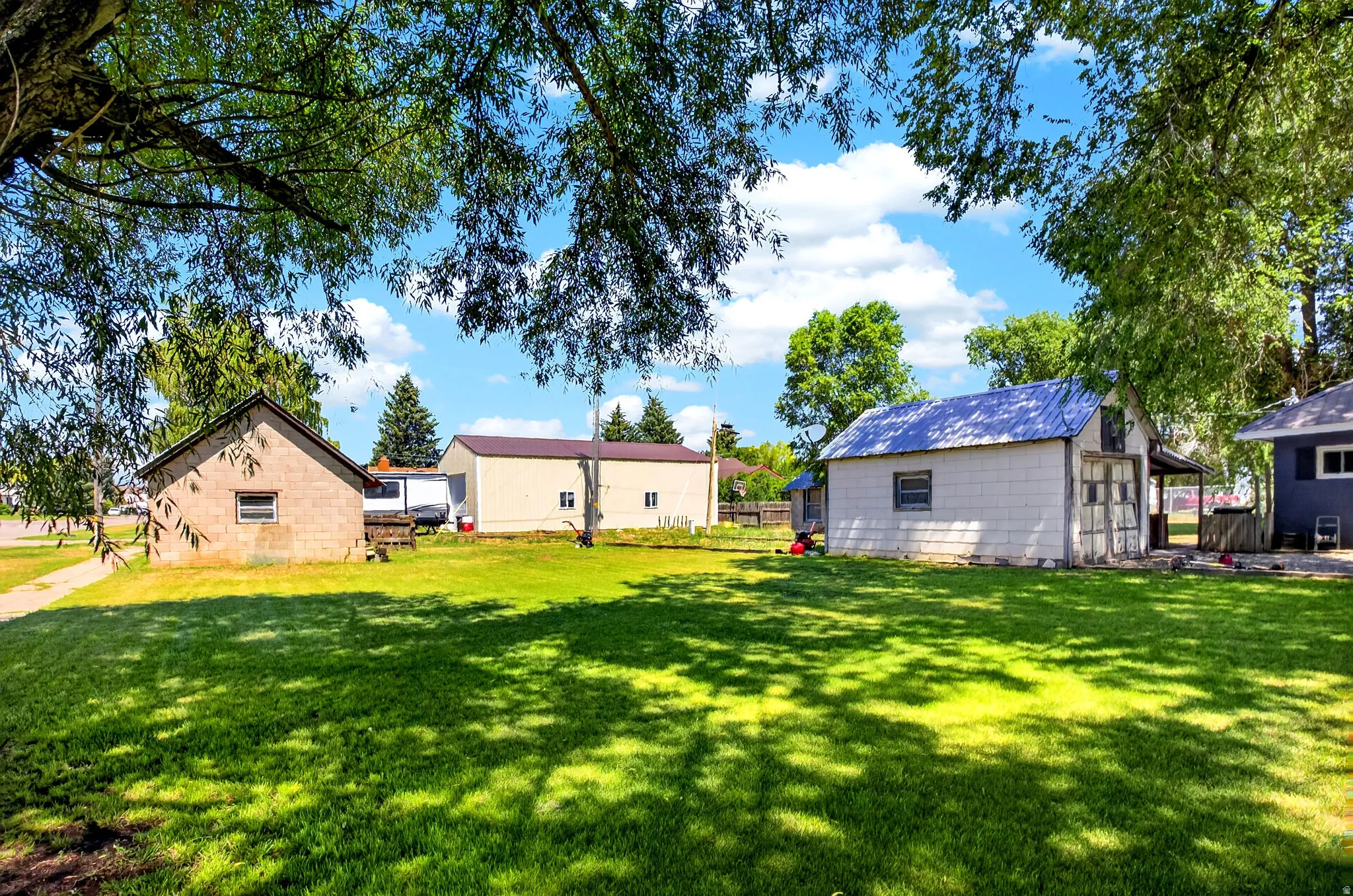 Expansive green lawn with mature trees providing dappled shade