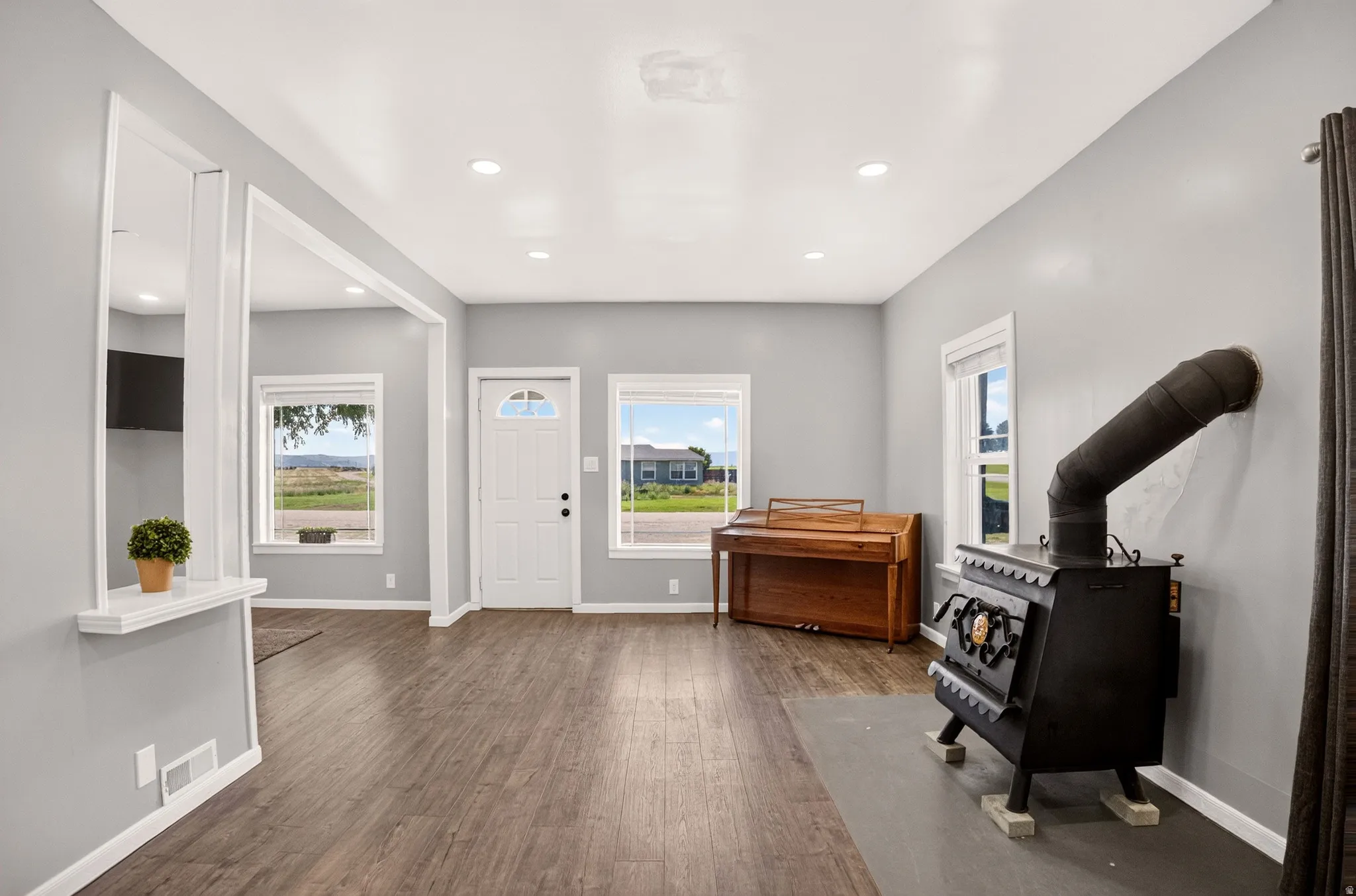 Open concept living space featuring wood-finish flooring, recessed lighting, and a wood-burning stove
