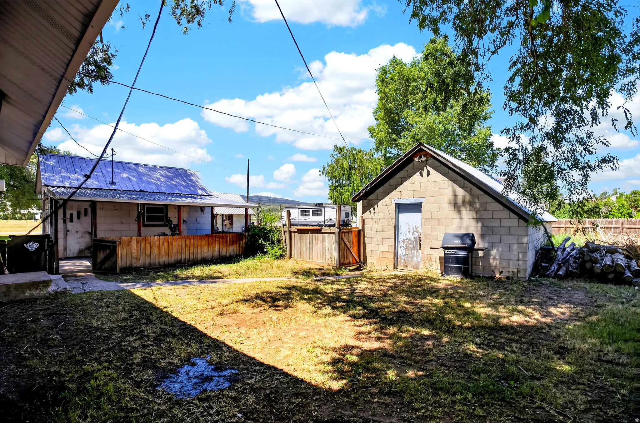 Expansive backyard featuring a concrete block outbuilding, a fenced perimeter, and mature trees