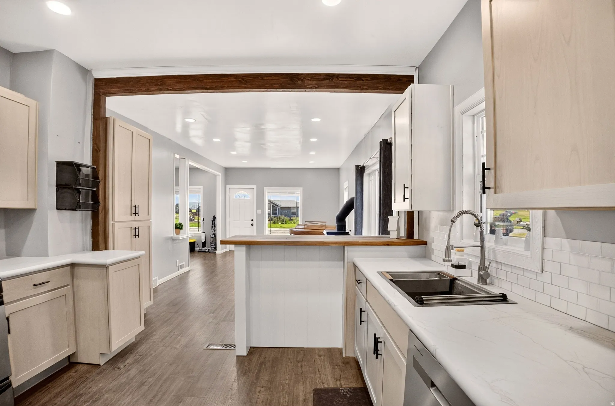 Kitchen featuring light-toned cabinetry, white countertops, a stainless steel sink with a pull-down faucet, and a white subway tile backsplash