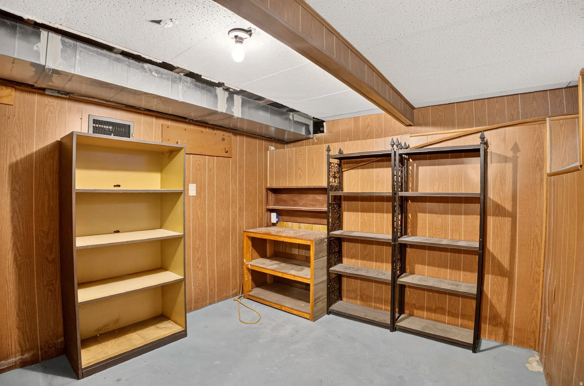Room with wood-panel walls, a drop ceiling, and exposed ductwork