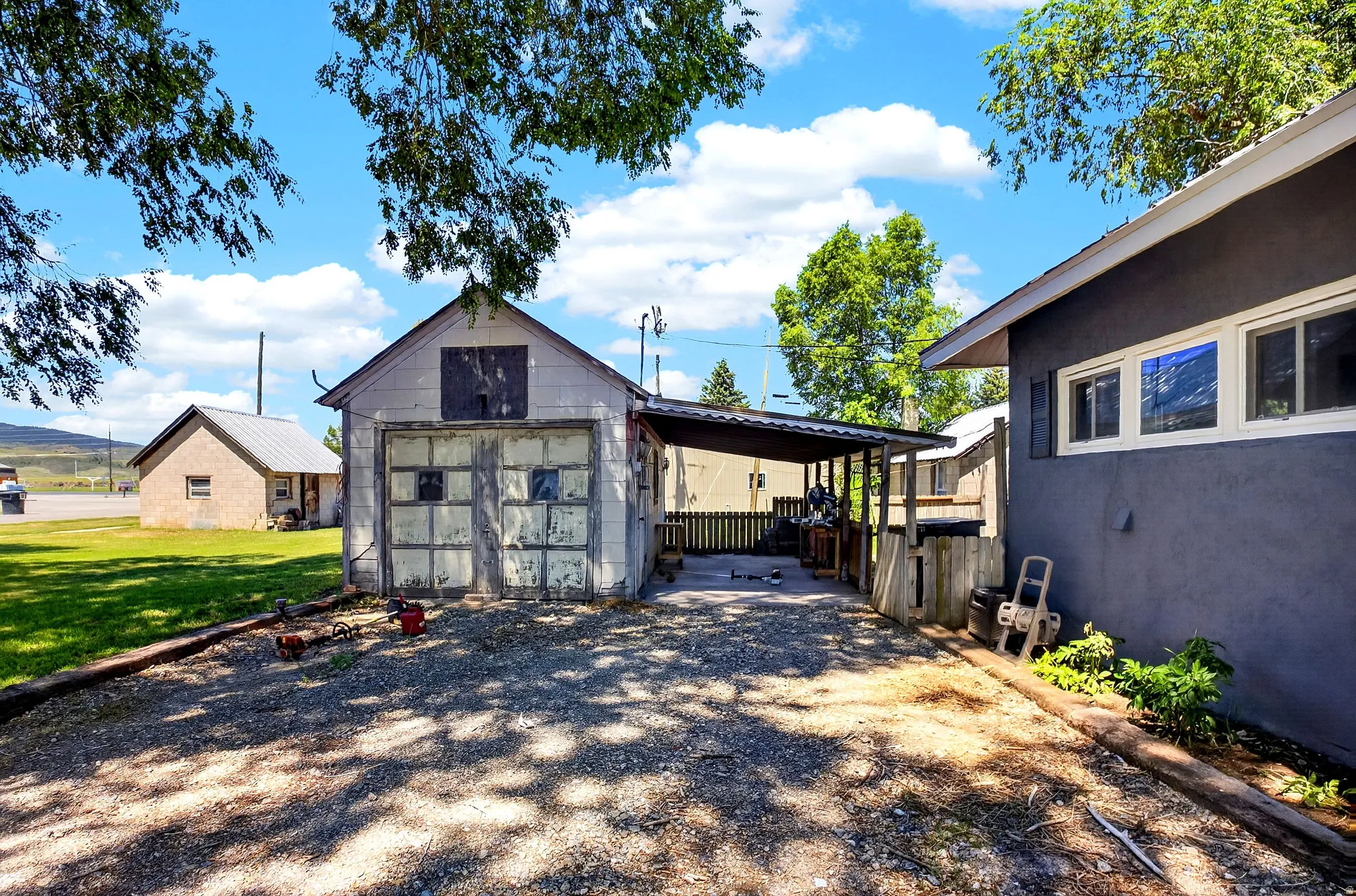 Gravel driveway with a detached garage and an attached carport