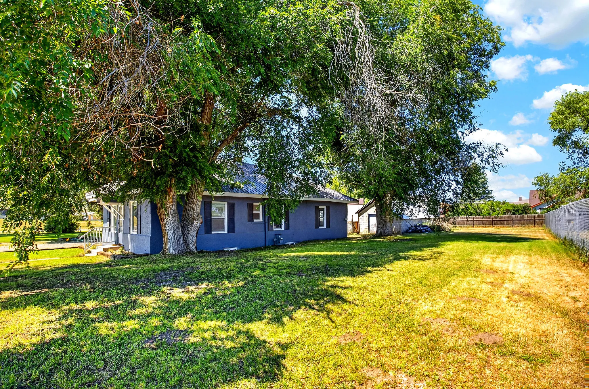Expansive grassy yard featuring mature trees providing ample shade