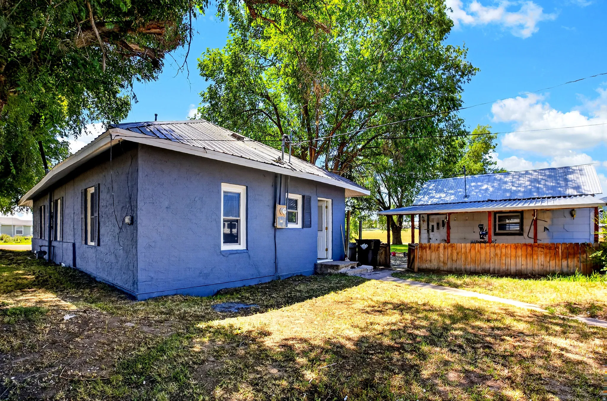 Exterior featuring stucco siding, white window trim, and a metal roof