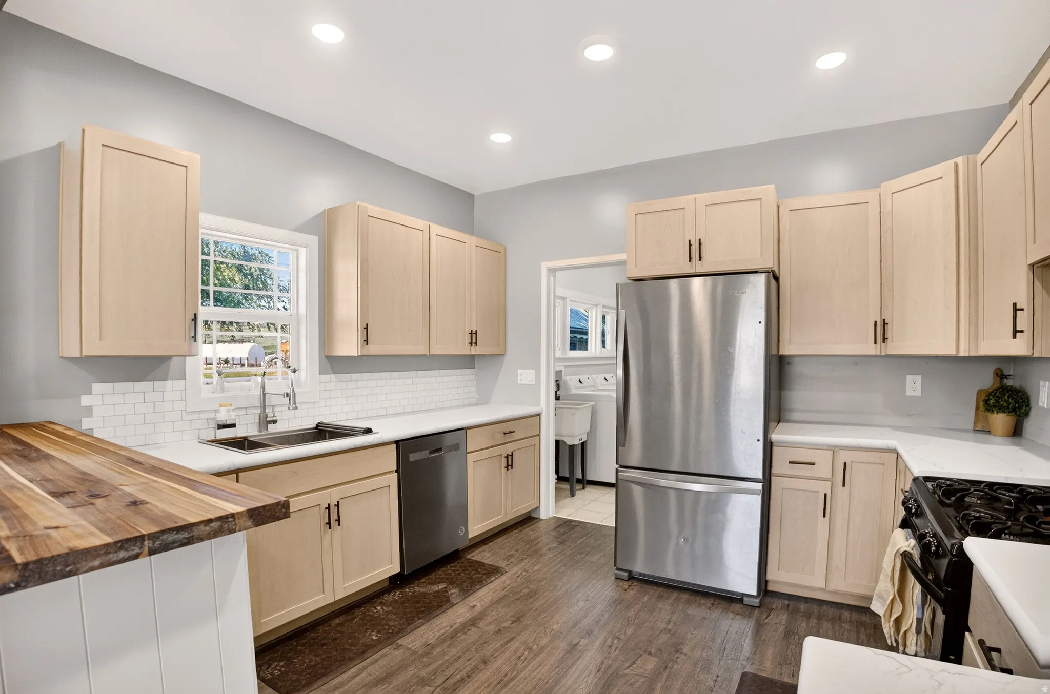 Kitchen featuring light wood-finish cabinetry, white countertops, and a white subway tile backsplash
