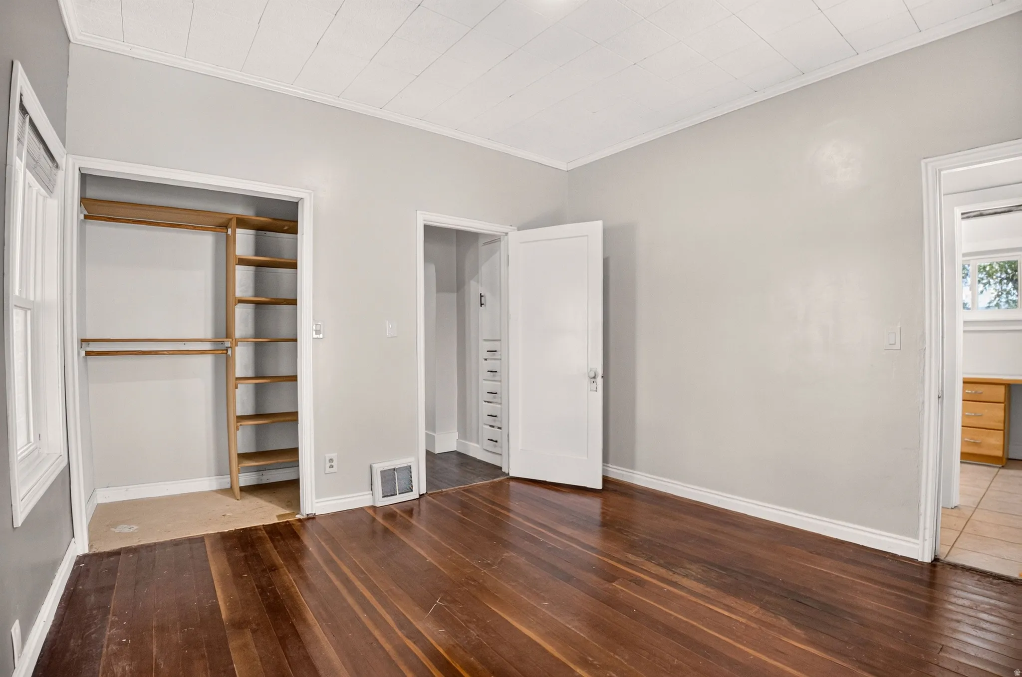 Room featuring wood-finish flooring, light grey painted walls, white baseboards, and a white ceiling with paneling