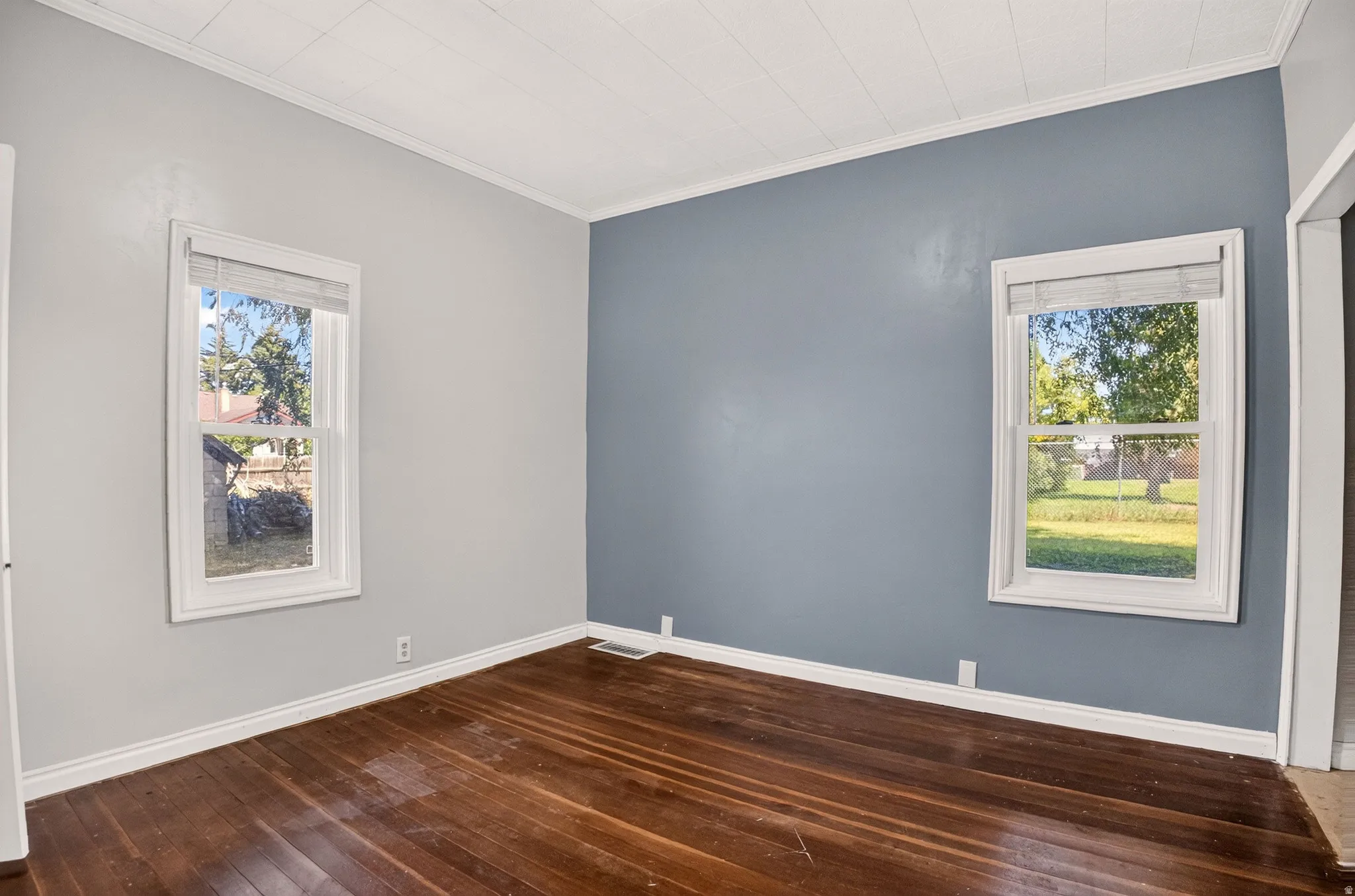 Room with wood-finish flooring, white baseboards, and a white beadboard ceiling