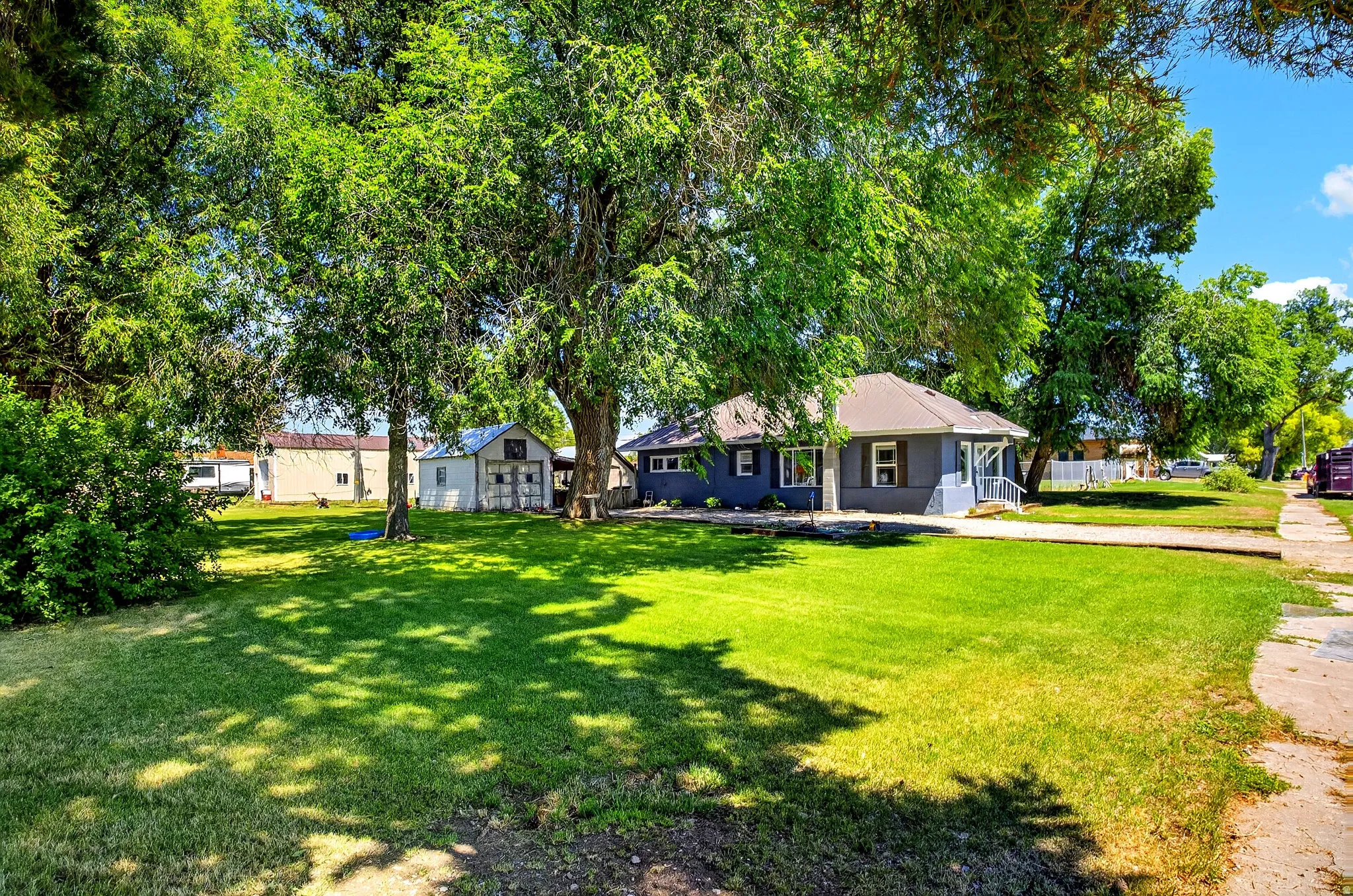 Expansive front yard featuring a manicured lawn and mature shade trees