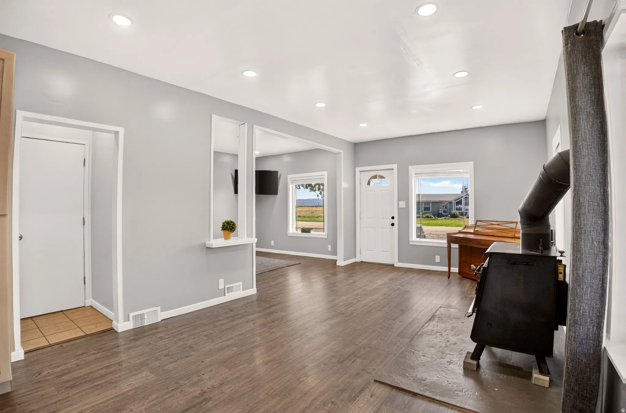 Open concept living space featuring wood-finish flooring, recessed lighting, and a wood-burning stove