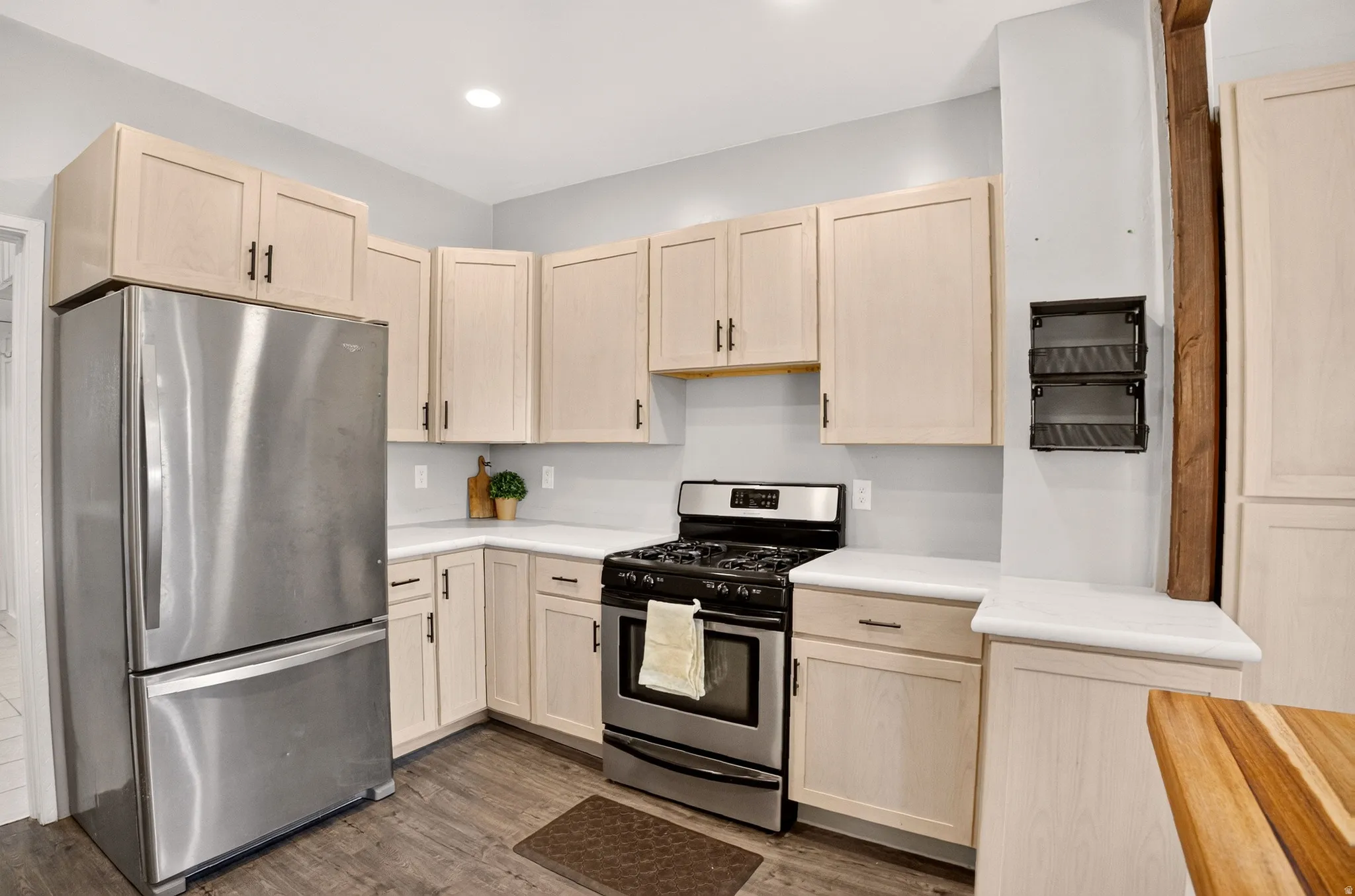Modern kitchen featuring stainless steel appliances, light wood-finish cabinetry, and white countertops