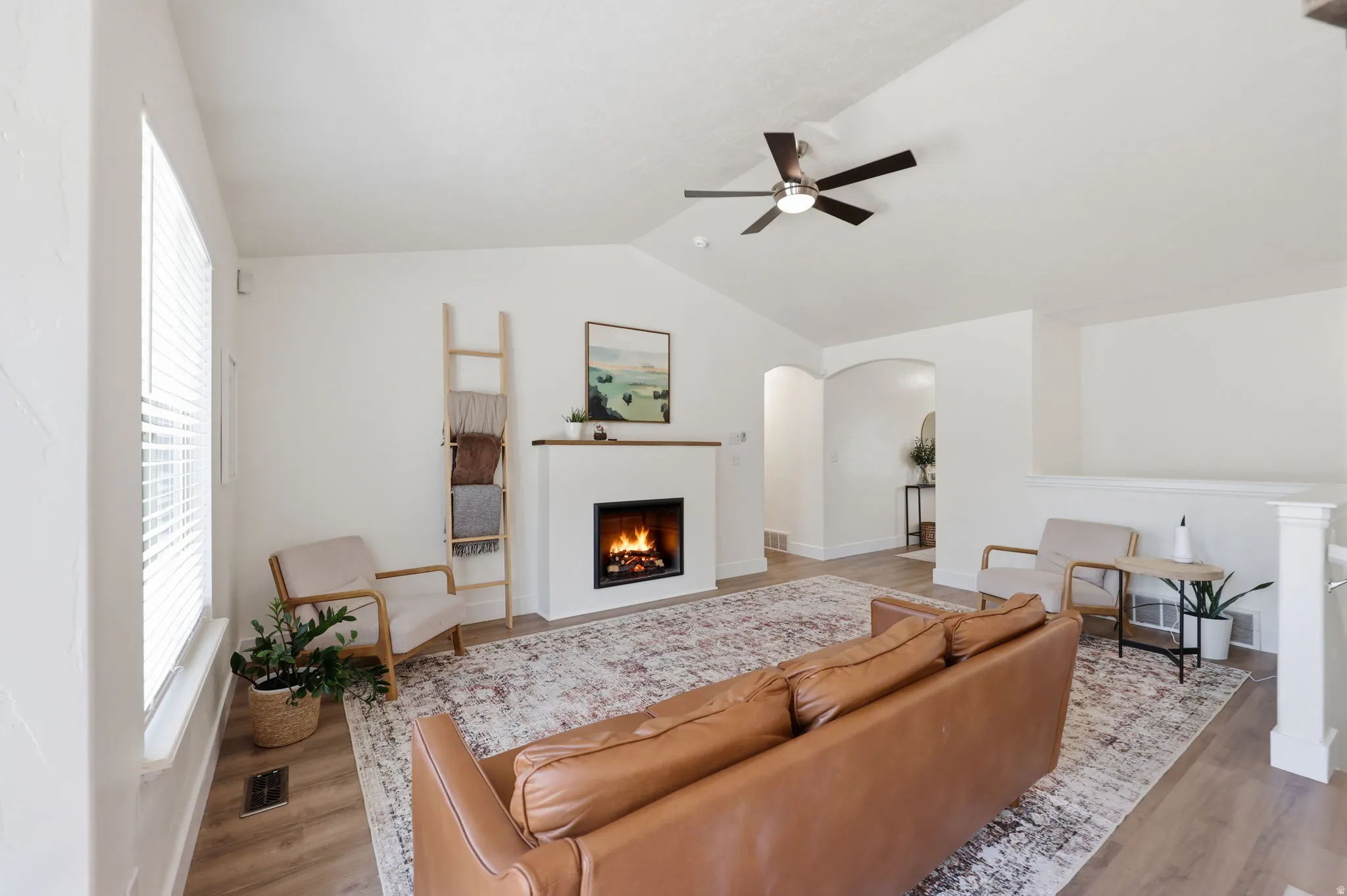 Living area featuring a fireplace with a wood mantle, vaulted ceilings, and wood-finish flooring