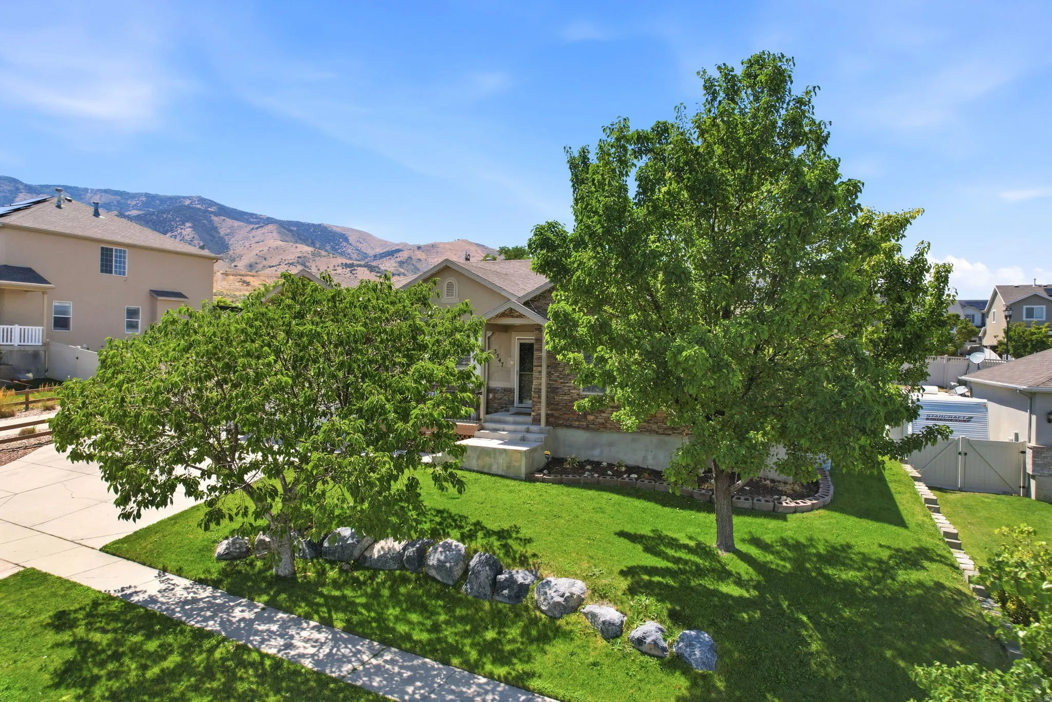 Front exterior with a stone facade, a concrete driveway, and a concrete walkway