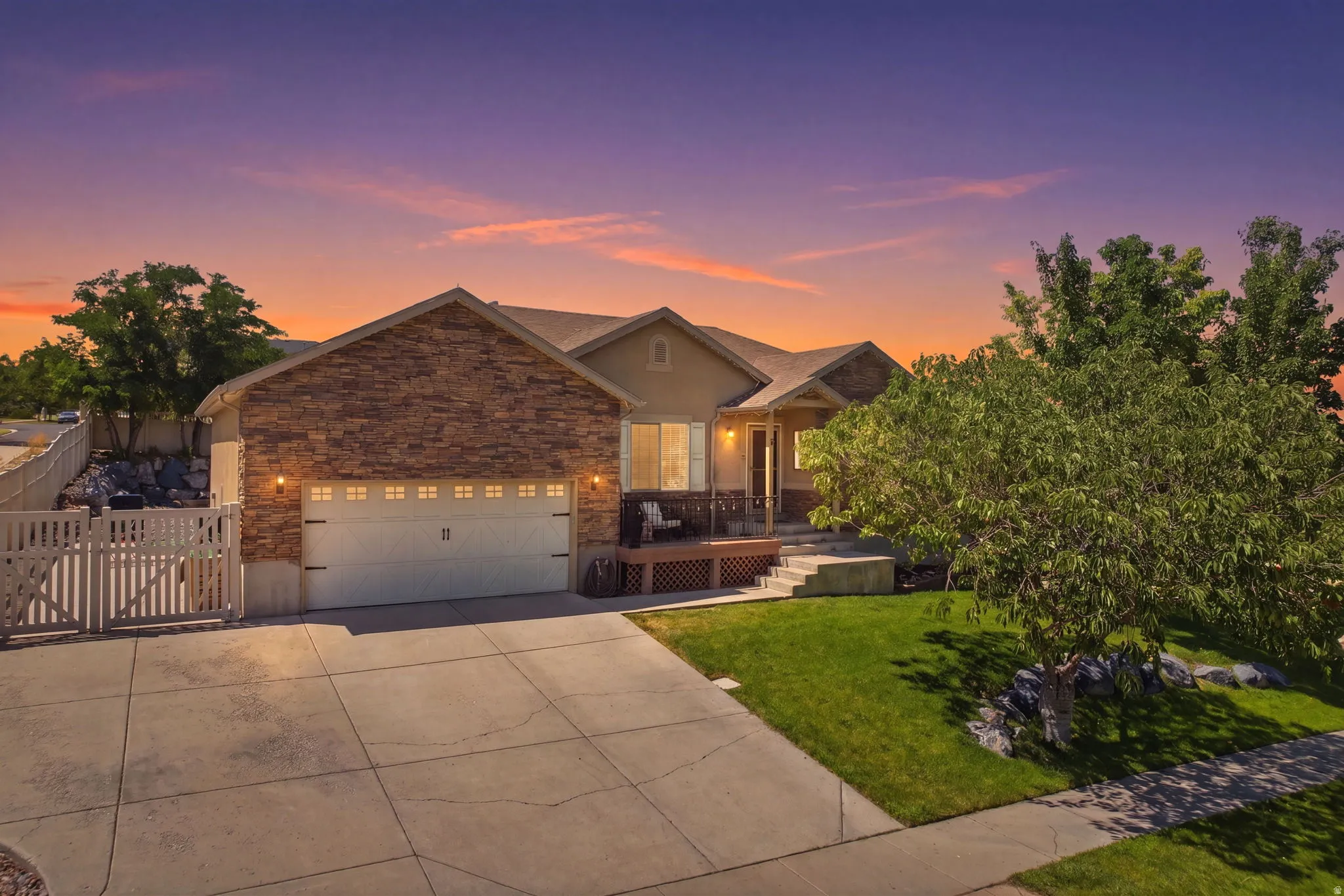 Single-story residence featuring a stone and stucco facade, an attached two-car garage with decorative hardware, a covered front porch, and a concrete driveway