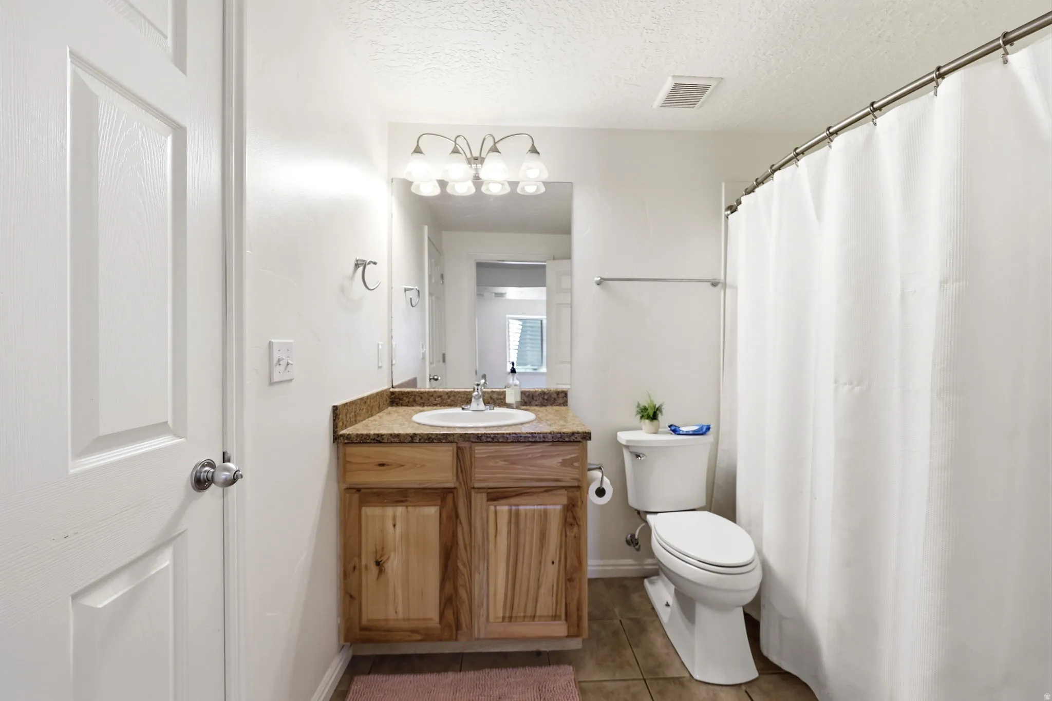 Bathroom featuring a wood-finish vanity with a built-in sink, a speckled countertop, and a vanity light fixture