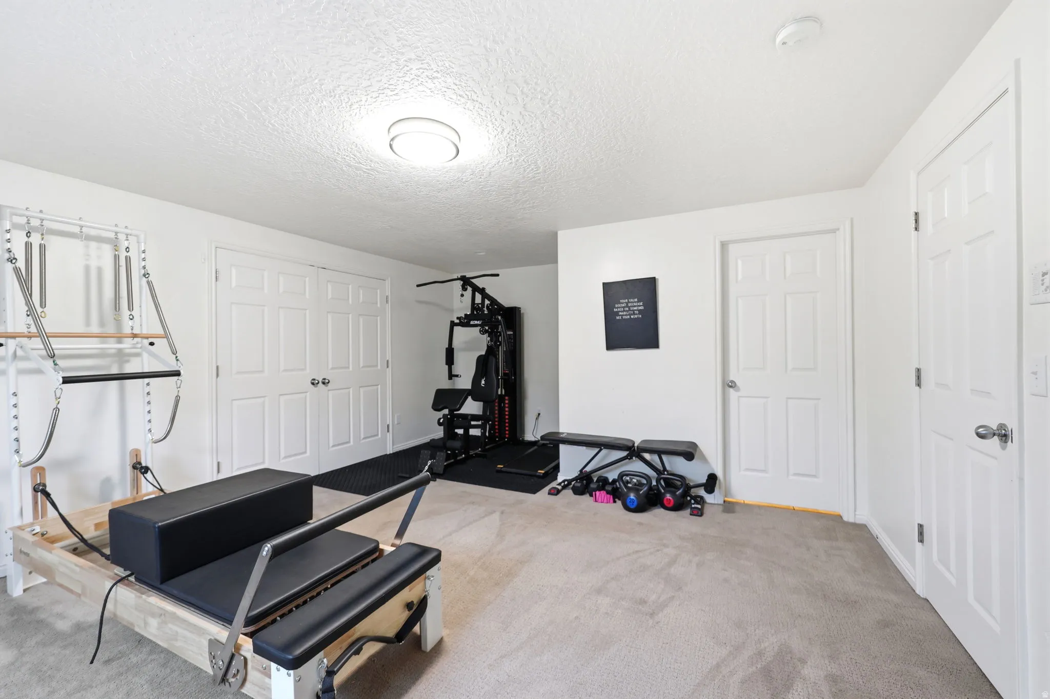 Versatile room with plush carpet flooring, multiple white paneled doors, and a ceiling-mounted light fixture