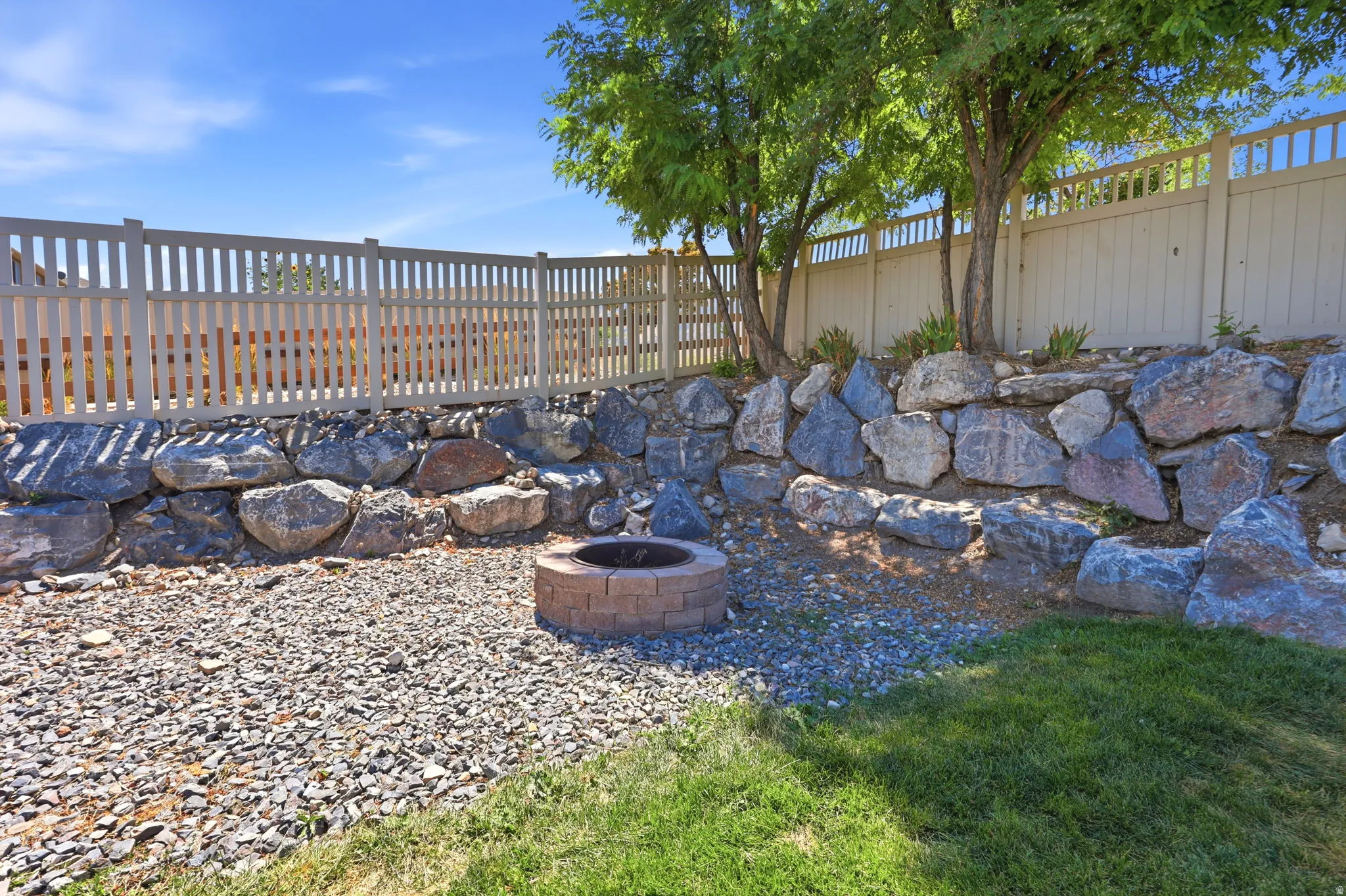 Outdoor living space featuring a built-in fire pit, a gravel ground covering, and a rock retaining wall