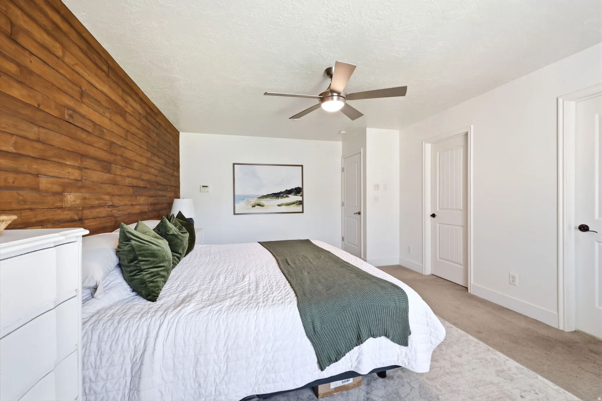 Bedroom featuring a wood accent wall, neutral carpeting, and a ceiling fan with integrated lighting