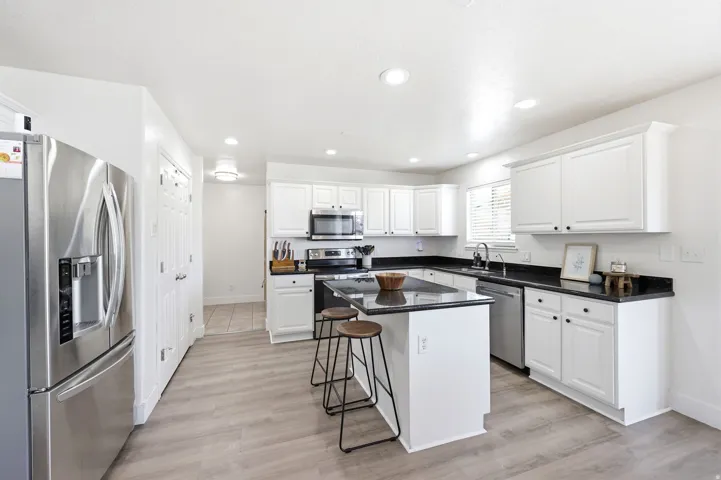 Spacious kitchen featuring an island, white cabinetry, dark countertops, and wood-finish flooring