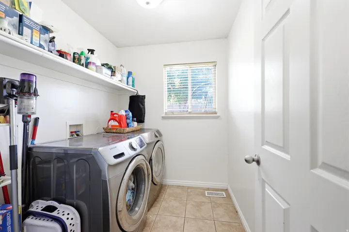 Laundry room featuring tile flooring, a window with blinds, and built-in shelving