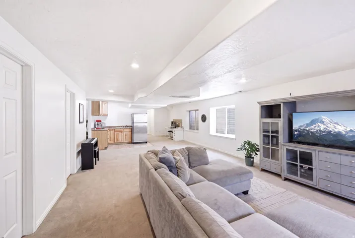 Spacious entertainment area featuring neutral-toned carpeting, recessed lighting, and a built-in media console