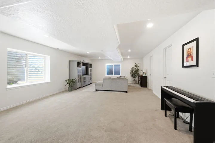 Spacious room featuring neutral carpeting, white walls, recessed lighting, and multiple egress windows
