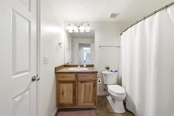 Bathroom featuring a wood-finish vanity with a built-in sink, a speckled countertop, and a vanity light fixture