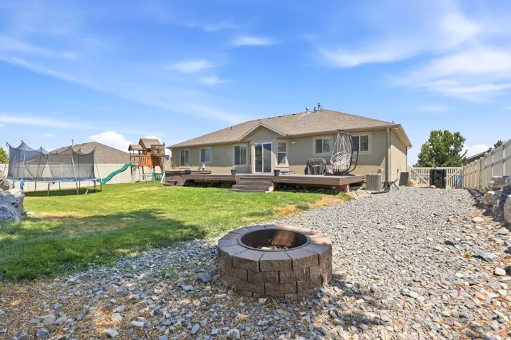 Expansive backyard featuring a stone block fire pit, a raised wood deck, and a manicured lawn