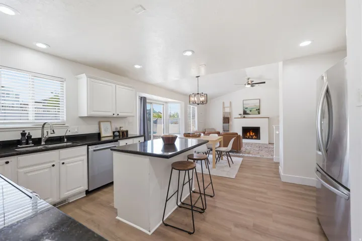 Kitchen featuring white cabinetry, dark countertops, and stainless steel appliances, with a breakfast bar and pendant lighting