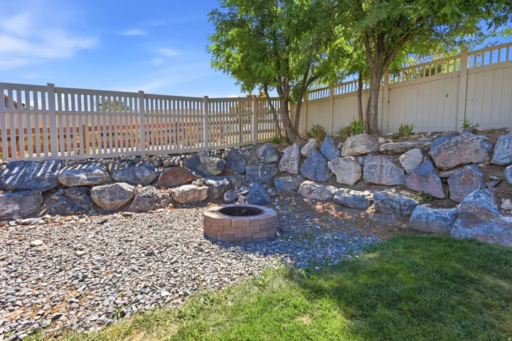 Outdoor living space featuring a built-in fire pit, a gravel ground covering, and a rock retaining wall