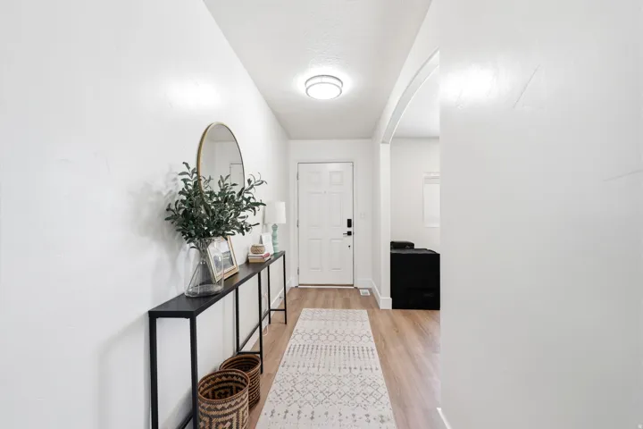 Entryway featuring light wood-finish flooring, white walls, and an arched doorway