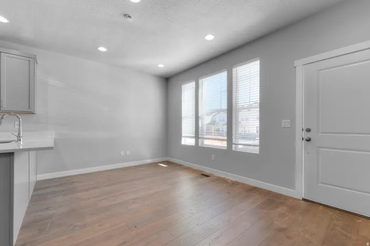 Wood-finish flooring, recessed lighting, and a white paneled door