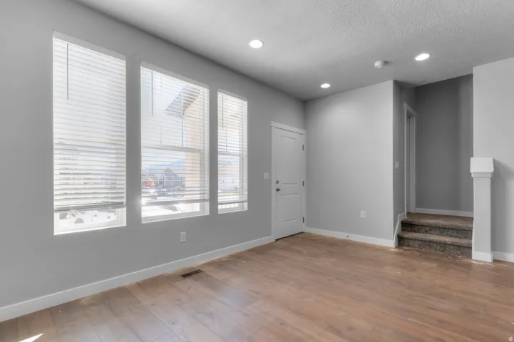 Wood-finish flooring with neutral wall tones and recessed lighting