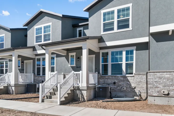 Grey stucco exterior with white trim, covered front porch, and ground-level windows