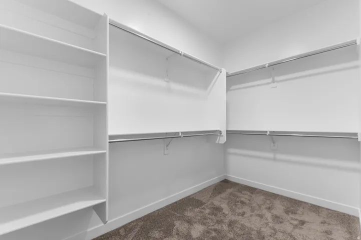 Built-in shelving, multiple hanging rods, and plush carpet flooring