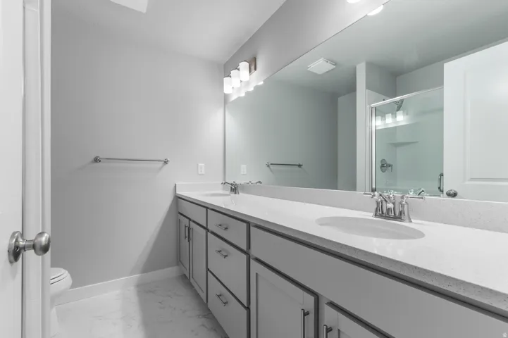 Dual vanity with a white countertop and integrated sinks, brushed nickel faucets, and a large wall-mounted mirror