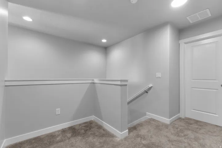 Recessed lighting, neutral-toned walls, and plush carpet flooring