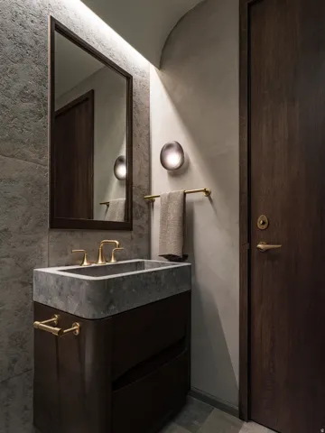 Integrated stone sink and vanity with dark wood-finish cabinetry, featuring brass-tone hardware and faucet