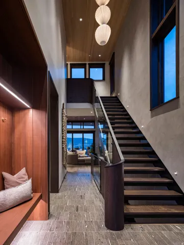 Floating dark wood stairs with a glass railing and wood-finish flooring