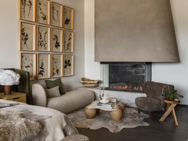 Dark wood-finish flooring complements a corner fireplace with a glass enclosure and a large, textured plaster-finish hood