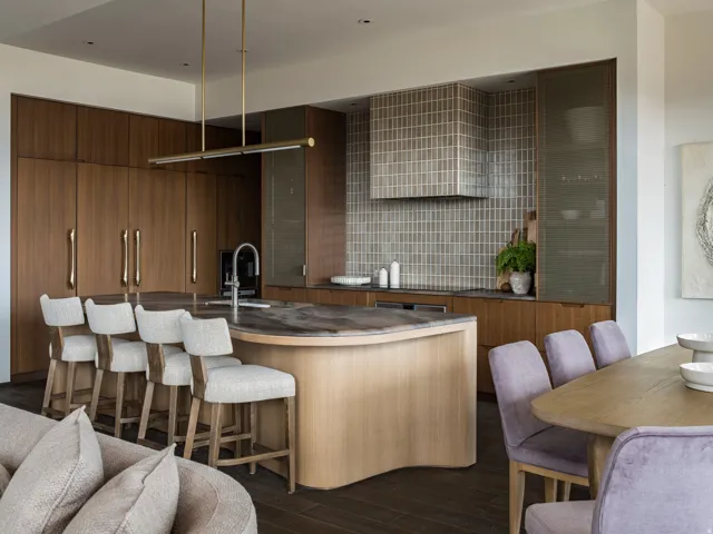 Open-concept kitchen with a curved island, integrated appliances, and wood-finish cabinetry