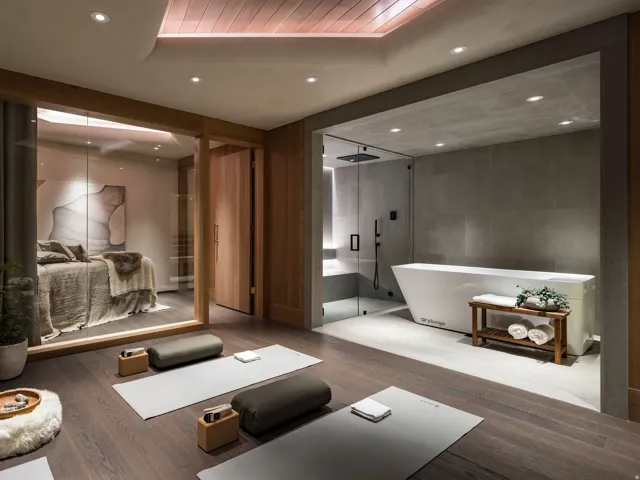 Wood-finish flooring throughout a dedicated wellness space featuring recessed lighting, a full bathroom with a glass-enclosed shower and soaking tub, and a separate room with a built-in bed