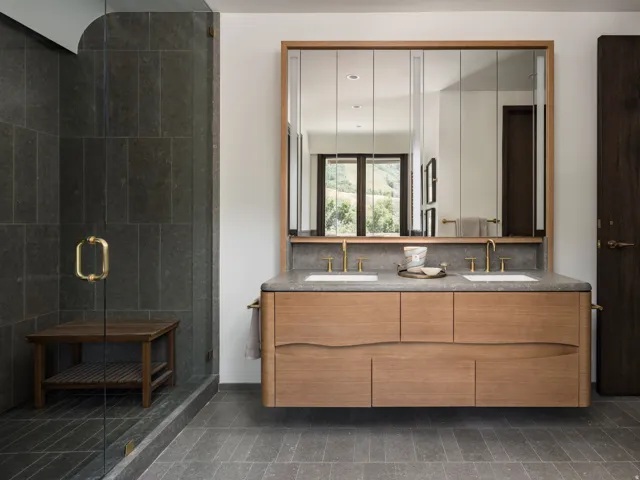 Floating dual vanity with integrated sinks, brass-finish fixtures, and a stone countertop