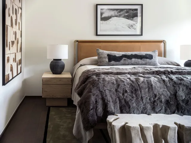 Bedroom featuring a leather-upholstered headboard, dark wood-finish flooring, and a light wood-tone nightstand with integrated drawers