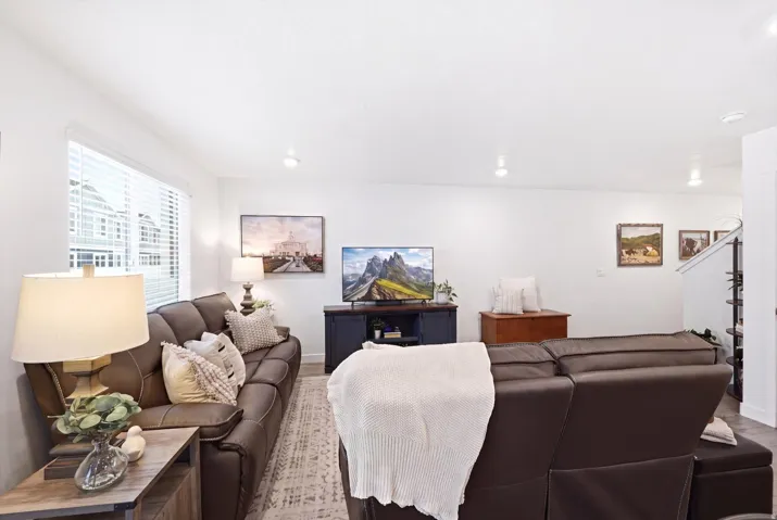 Spacious living area featuring white walls, recessed lighting, and large windows with horizontal blinds