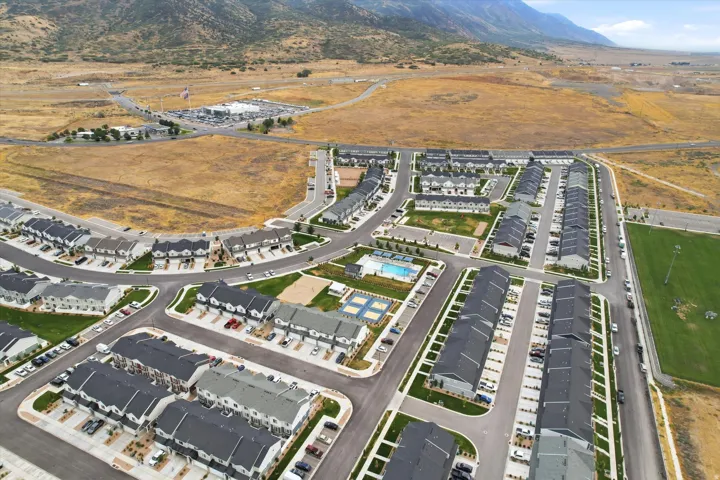 Expansive residential development featuring multiple rows of townhomes, a central swimming pool, paved roadways, and green spaces