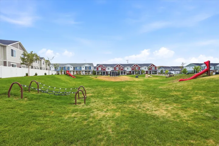 Expansive green space featuring a rope climbing structure and two red slides